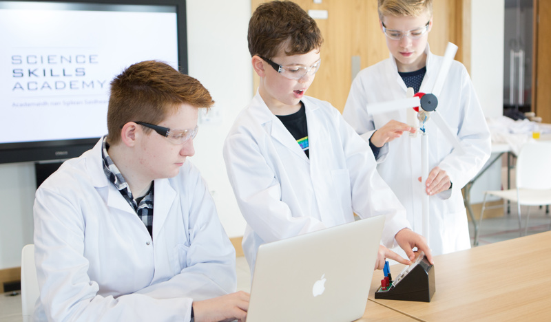 3 students wearing white lab coats doing an experiment in the Science Skills Academy