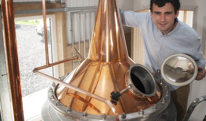 Man standing by gin still at Dunnet Bay Distillery