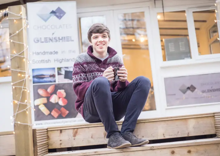 Young Highland chocolatier, Finlay Mackenzie, sitting outside his Wester Ross shop