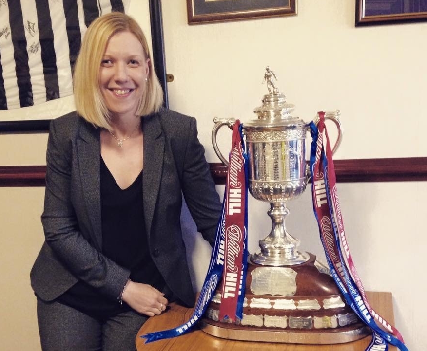 woman posing with large silver trophy