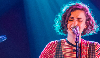 Woman singing at XpoNorth backlit by blue light