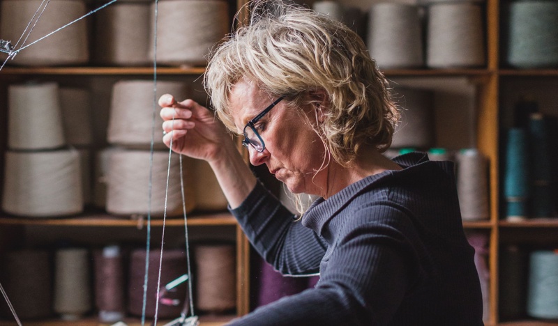 Woman sitting at Hume Sweet Hume knitting machine