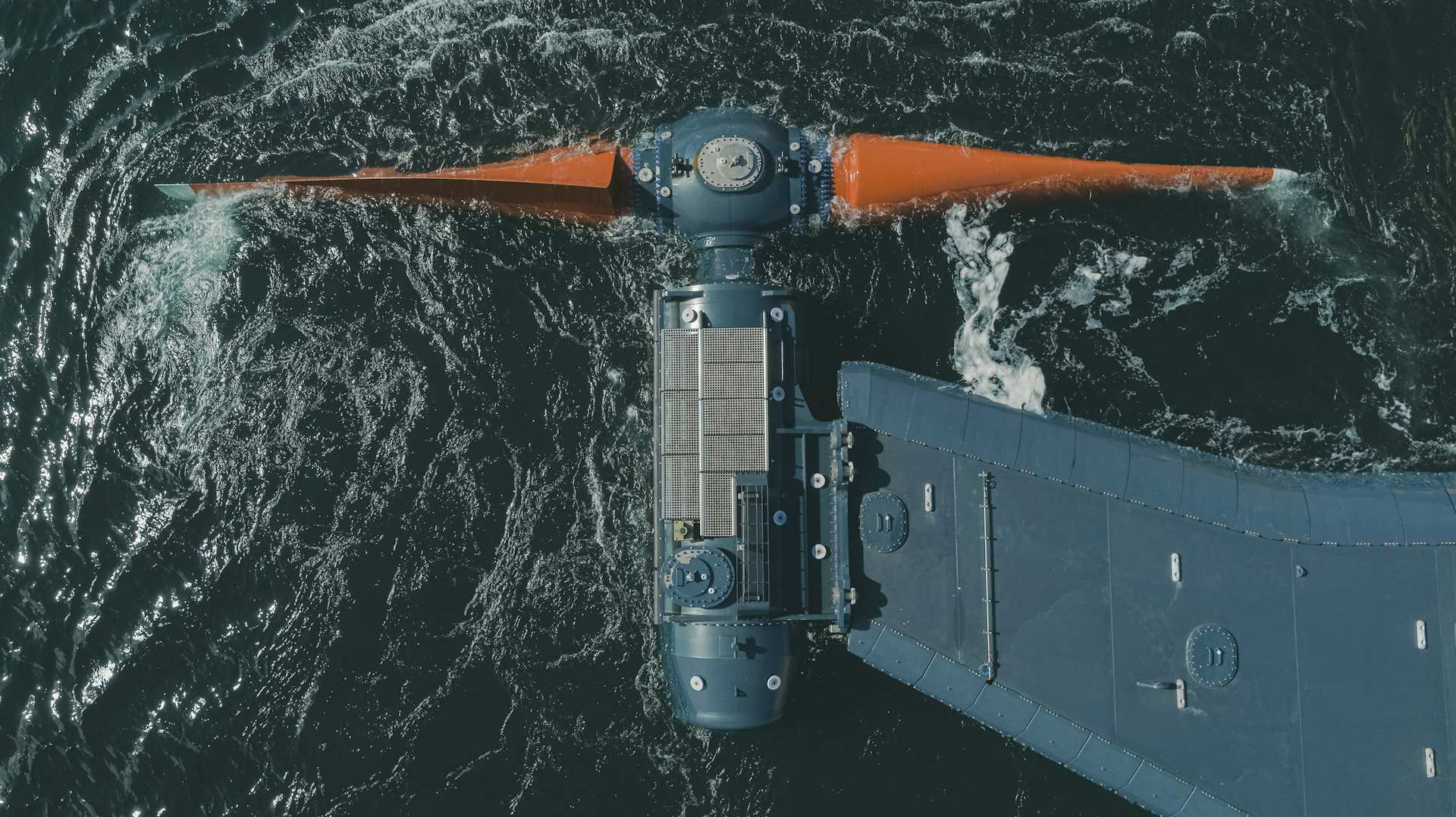 Orbital turbine, t-shaped with large orange blades at the front in the dark ocean offshore of Orkney 